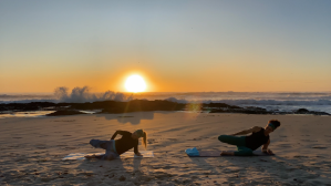 Ascension Active instructors doing a seven-minute stretch on the beach at sunrise