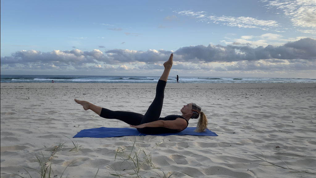 Ascension Active instructor doing Pilates series of five on the beach